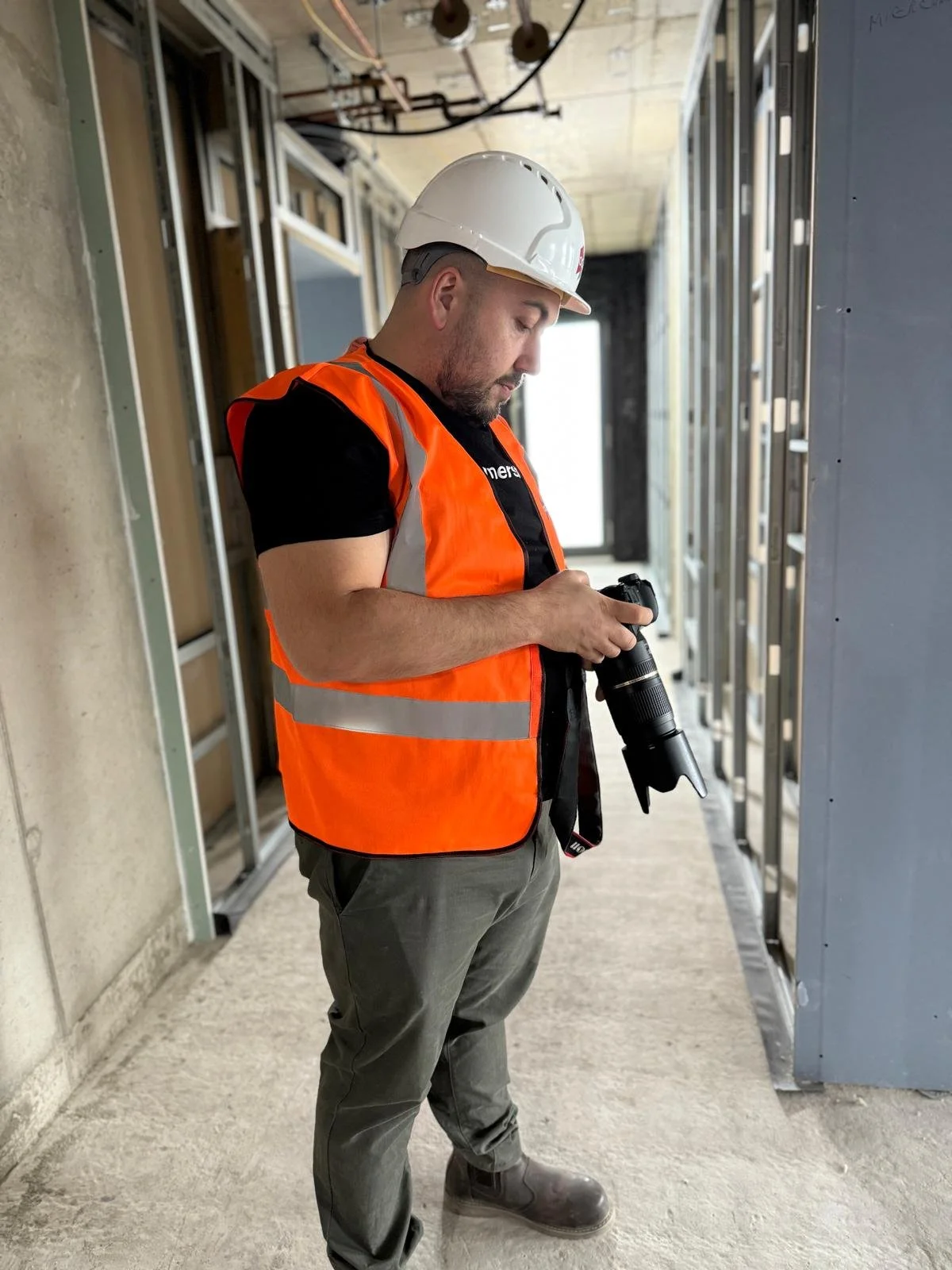 Theo Tziapouras photographing on site in hi-vis and hard hat